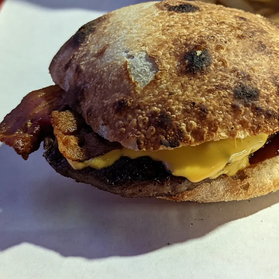 Pizza burger con bacon e cheddar fuso, il pane bruciacchiato dal forno